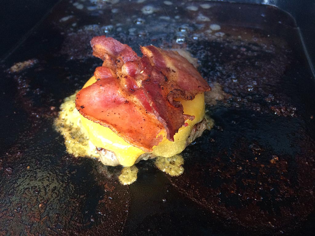 Burger smothered with melted cheddar cheese and bacon