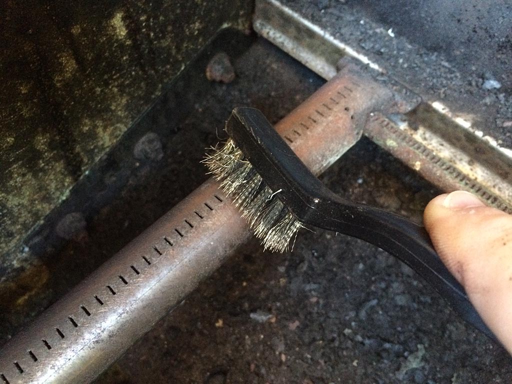 Cleaning burner holes with stainless steel brush