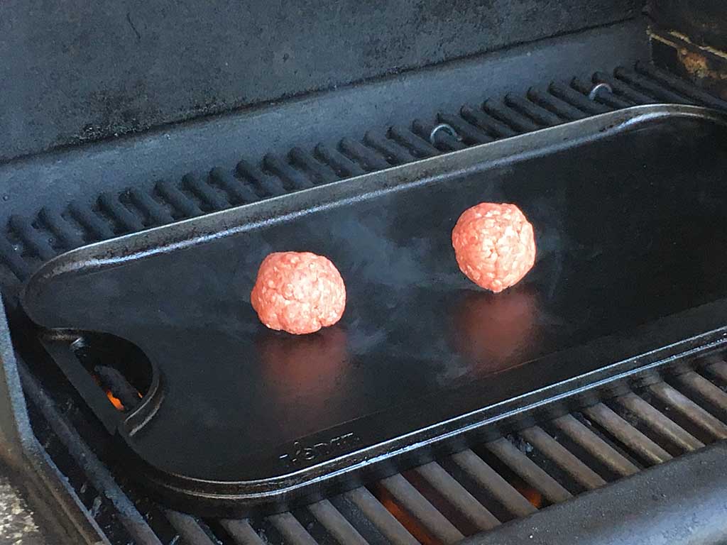 Two ground beef balls on the griddle