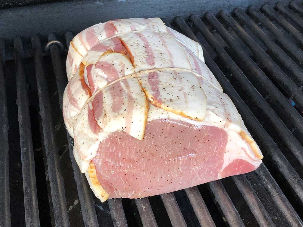Bacon wrapped, garlic sausage stuffed pork loin goes into Weber Summit