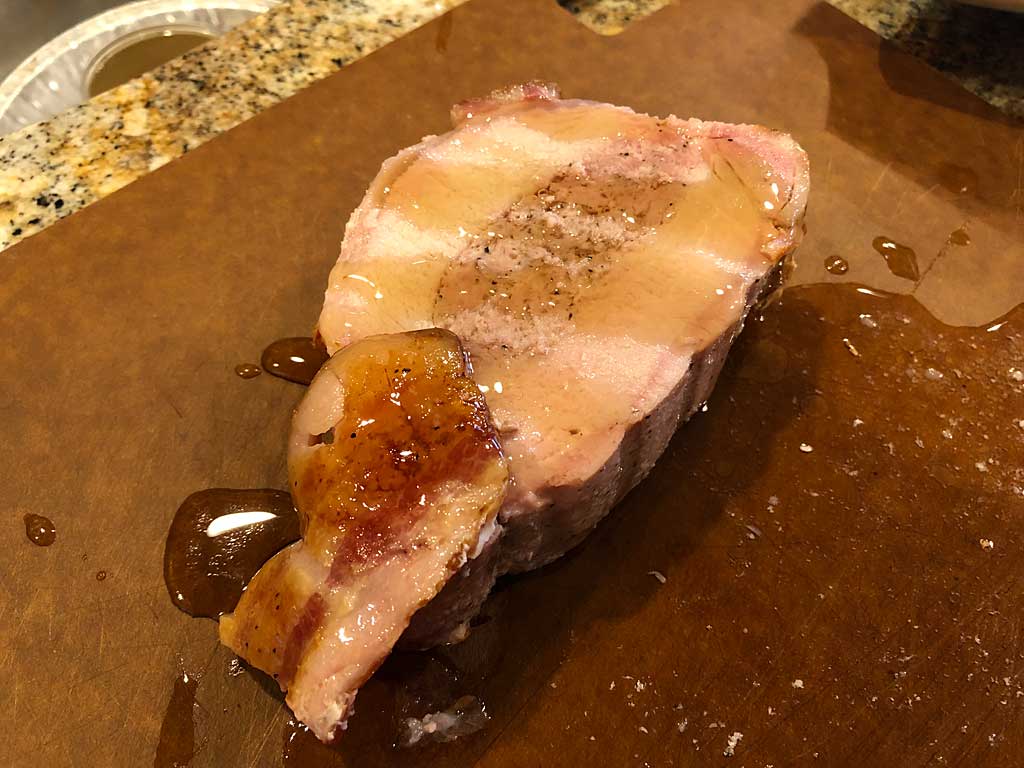 Slice of bacon wrapped, garlic sausage stuffed pork loin