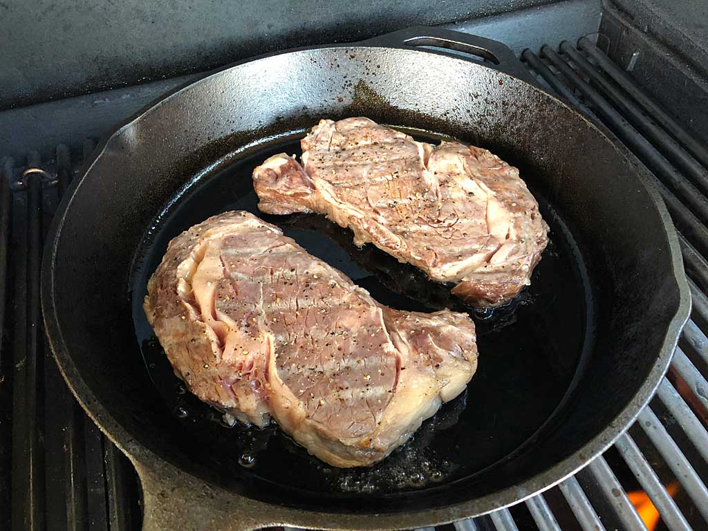 Steaks searing in cast iron skillet