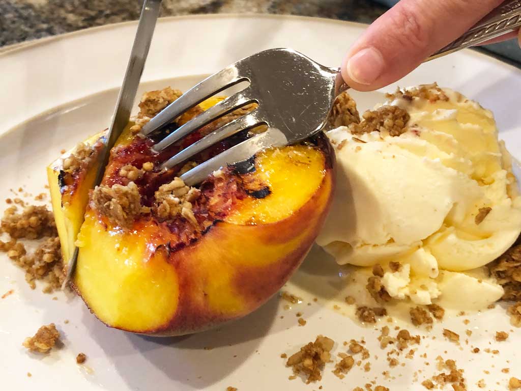 Cutting grilled peach on plate